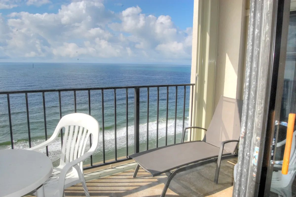 A private balcony featuring outdoor furniture with an expansive ocean view under a cloudy sky. The balcony is clearly a serene retreat, inviting guests to relax, enjoy the sea breeze, and soak in the sunrise or sunset with a cup of coffee or book in hand.
